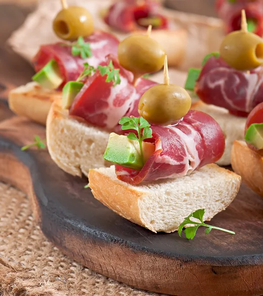 Snack on toast with ham, avocado and olives — Stock Photo, Image