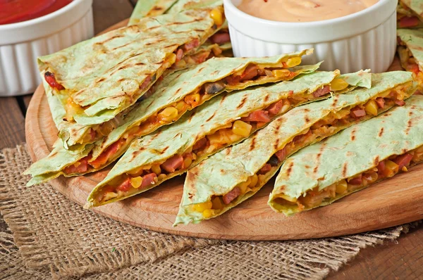 Quesadilla mexicano fatiado com legumes e molhos na mesa — Fotografia de Stock