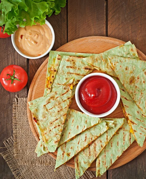 Quesadilla mexicano fatiado com legumes e molhos na mesa — Fotografia de Stock