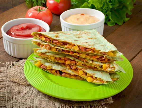 Quesadilla mexicano fatiado com legumes e molhos na mesa — Fotografia de Stock