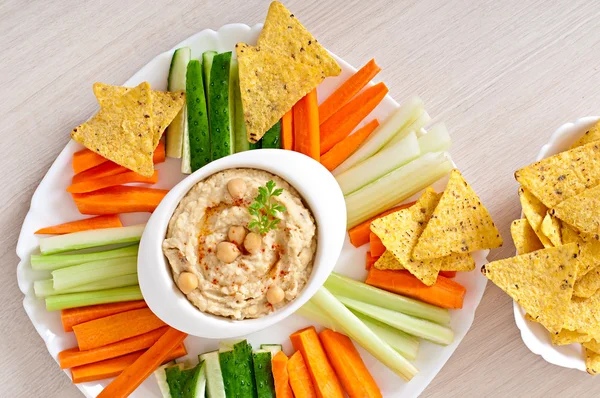 Hummus with vegetables, olive oil and pita chips — Stock Photo, Image