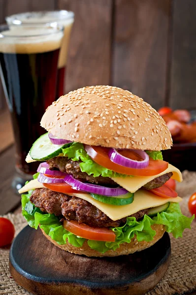 Large burger with meat and vegetables and beer — Stock Photo, Image
