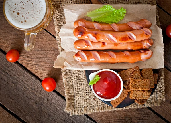 Grillwürste mit Croutons, Ketchup und Bier — Stockfoto