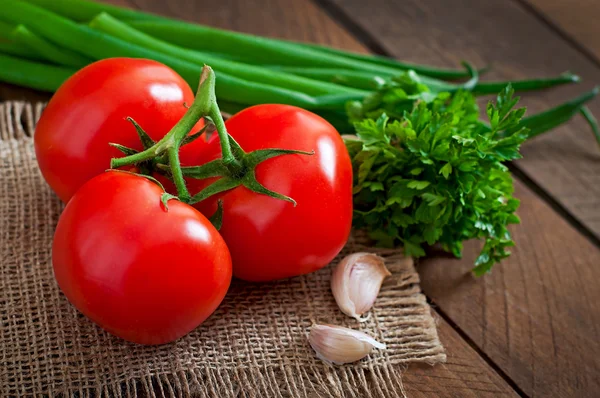 Branche de tomates fraîches, oignons et légumes verts — Photo