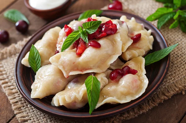 Dumplings with cherries and leaves — Stock Photo, Image