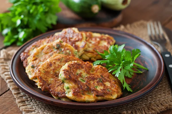 Courgettepannenkoeken met peterselie op een houten tafel. — Stockfoto