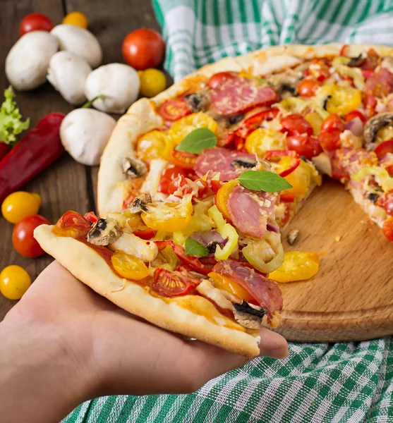 Bit av pizza i hand — Stockfoto
