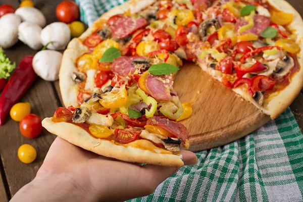 Bit av pizza i hand — Stockfoto