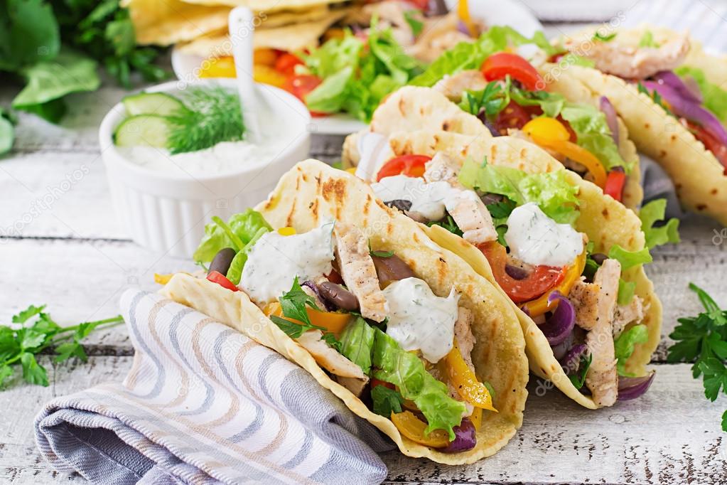 Mexican tacos with chicken, bell peppers, black beans and fresh vegetables and tartar sauce