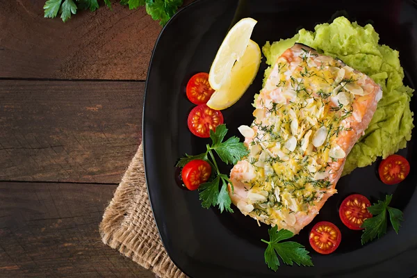 Baked salmon with cheese and almond crust and garnished with mashed potatoes and green peas — Stock Photo, Image