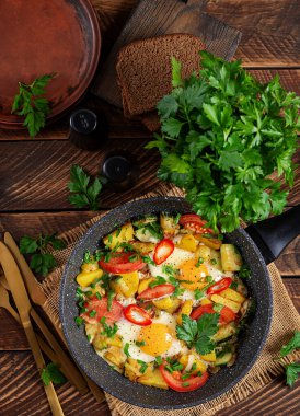 Fried eggs and potatoes, tomatoes, zucchini  and chili peppers in a rustic style.  Top view