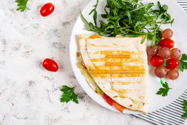 Healthy breakfast. Lavash with cheese, tomatoes, and herbs. Fresh salad. Top view