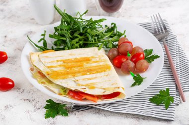 A healthy breakfast. Lavash with cheese, tomatoes, and herbs. Fresh salad.