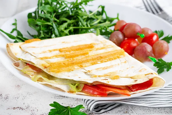 A healthy breakfast. Lavash with cheese, tomatoes, and herbs. Fresh salad.