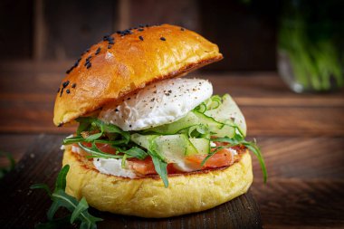 Bun breakfast sandwich with salt salmon, cream cheese and poached egg