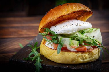 Bun breakfast sandwich with salt salmon, cream cheese and poached egg
