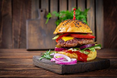 Beef hamburger. Sandwich with beef burger, tomatoes, cheese, pickled cucumber, red onions and ketchup. Cheeseburger