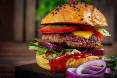 Beef hamburger. Sandwich with beef burger, tomatoes, cheese, pickled cucumber, red onions and ketchup. Cheeseburger