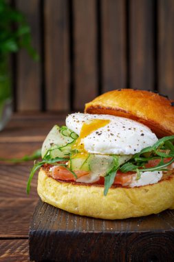 Bun breakfast sandwich with salt salmon, cream cheese and poached egg