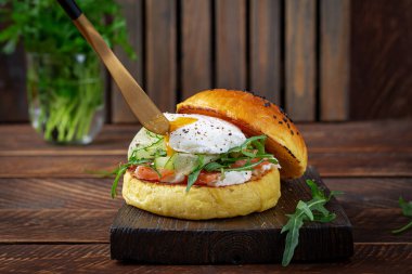 Bun breakfast sandwich with salt salmon, cream cheese and poached egg