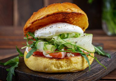 Bun breakfast sandwich with salt salmon, cream cheese and poached egg
