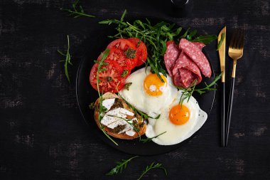 İngiliz kahvaltısı. Yağda yumurta, salam, domates ve peynirli tost. Üst görünüm.