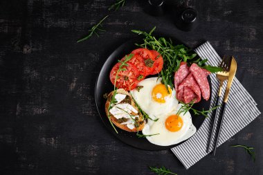 İngiliz kahvaltısı. Yağda yumurta, salam, domates ve peynirli tost. Üst görünüm.