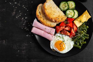 İngiliz kahvaltısı - kızarmış yumurta, jambon, yeşil fasulye, domates, salatalık ve tost. Üst görünüm