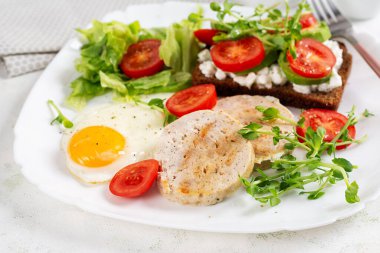 İngiliz kahvaltısı. Yağda yumurta, tavuklu köfte ve domatesli sandviç, avokado ve peynir..