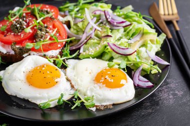 Kızarmış yumurta, taze salata ve domatesli sandviç, pesto ve krem peynir..