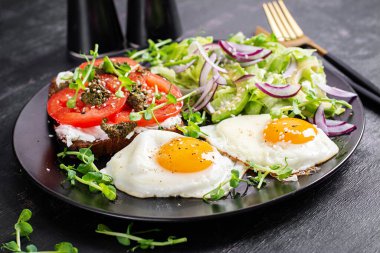 Kızarmış yumurta, taze salata ve domatesli sandviç, pesto ve krem peynir..