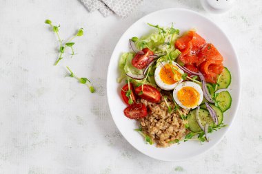 Kahvaltı yulaf lapası haşlanmış yumurta, tuzlu somon, domates, salatalık ve kırmızı soğan. Sağlıklı dengeli yiyecekler. Moda yiyecekler.