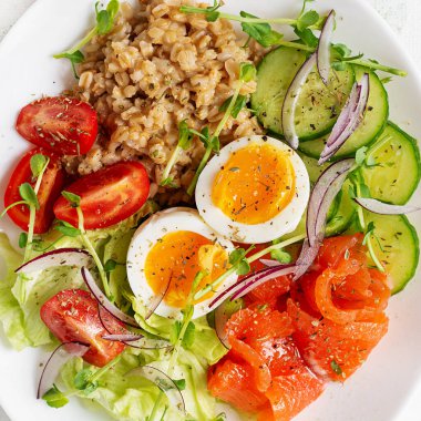 Kahvaltı yulaf lapası haşlanmış yumurta, tuzlu somon, domates, salatalık ve kırmızı soğan. Sağlıklı dengeli yiyecekler. Moda yiyecekler.