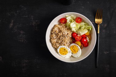 Sağlıklı kahvaltı. Bir kase yulaf ezmesi, taze sebze ve haşlanmış yumurta. Üst görünüm.