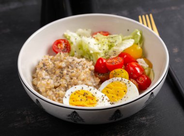 Sağlıklı kahvaltı. Bir kase yulaf ezmesi, taze sebze ve haşlanmış yumurta..