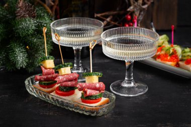 Salamlı, peynirli, domatesli kanepeler. Noel ve yeni yıl yemekleri. Tatil masası için atıştırmalık ve şarap..