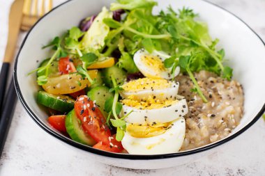 Sağlıklı kahvaltı kasesi yulaf ezmesi, haşlanmış yumurta ve taze sebze..