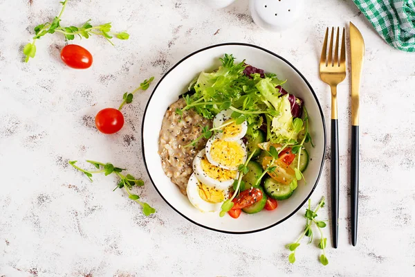 Sağlıklı kahvaltı kasesi yulaf ezmesi, haşlanmış yumurta ve taze sebze. Üst görünüm