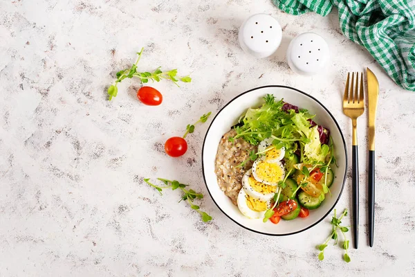 Sağlıklı kahvaltı kasesi yulaf ezmesi, haşlanmış yumurta ve taze sebze. Üst görünüm