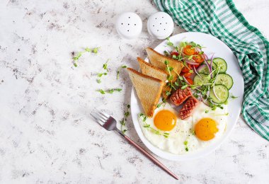 Yağda yumurta, ızgara sosis, domates, salatalık, yeşil ve baharatlı nefis bir kahvaltı. Üst görünüm