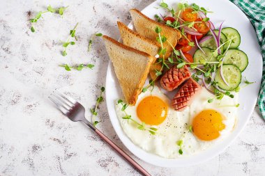 Yağda yumurta, ızgara sosis, domates, salatalık, yeşil ve baharatlı nefis bir kahvaltı. Üst görünüm