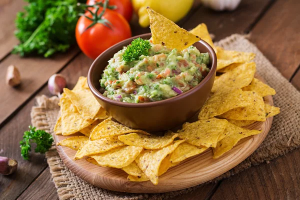 Guacamole Avocado, Limetten, Tomaten, Zwiebeln und Koriander, serviert mit Nachos — Stockfoto