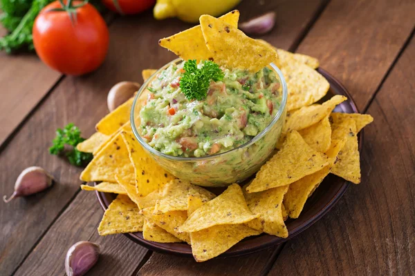 Guacamole abacate, limão, tomate, cebola e coentro, servido com nachos — Fotografia de Stock