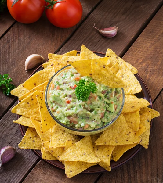 Guacamole Avocado, Limetten, Tomaten, Zwiebeln und Koriander, serviert mit Nachos — Stockfoto