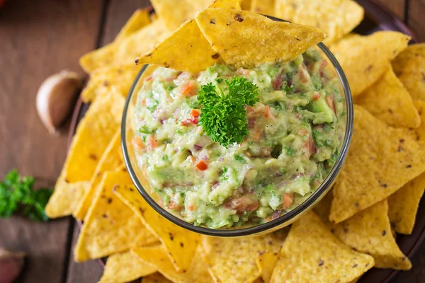 Guacamole alpukat, kapur, tomat, bawang bombay dan cilantro, disajikan dengan nachos — Stok Foto