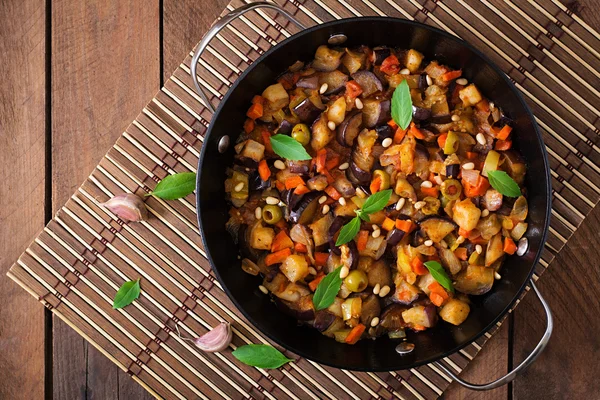 Італійський Caponata з сковороду на фоні дерев'яні — стокове фото