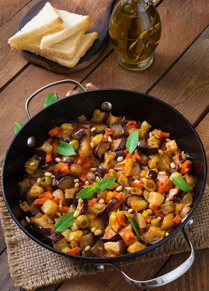 Italian Caponata with frying pan on a wooden background — Stock Photo, Image