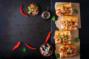 Hot dog - sandwich with Mexican salsa on dark background. T