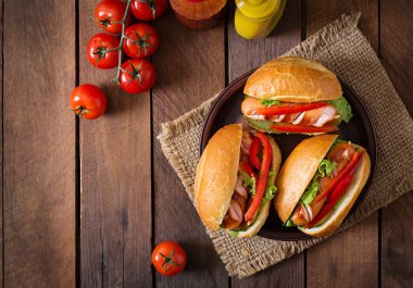 Hot dog - turşu, kırmızı biber ve marul üzerine ahşap arka plan ile sandviç