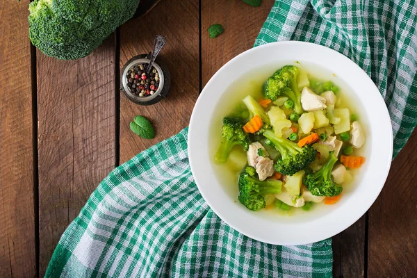 Soupe de poulet au brocoli, pois verts, carottes et céleri dans un bol blanc sur fond de bois — Photo